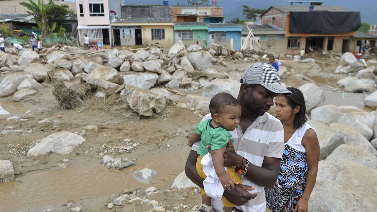 A man holds his son as he stands amid the remains of Mocoa.