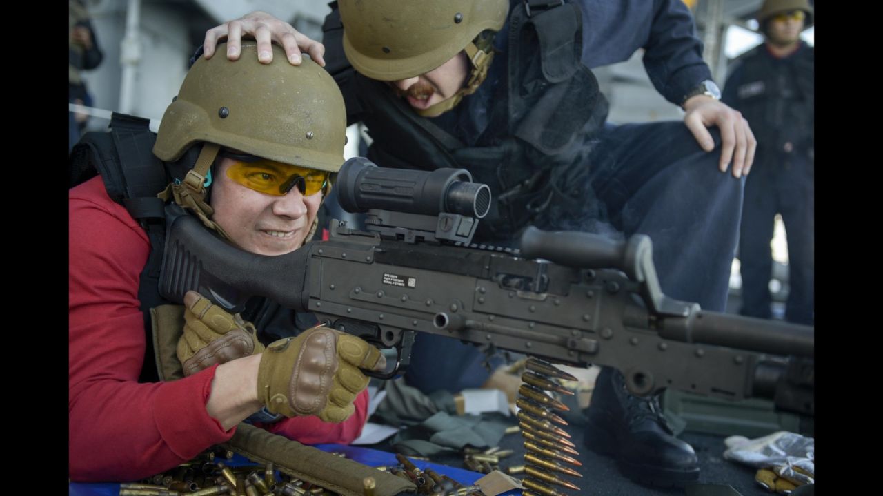 US Navy Lt. J.G. Virgilio Fermin fires an M240 machine gun while being instructed by Petty Officer 1st Class William Elliott on Monday, March 20. It was a live-fire exercise aboard the USS Nimitz, which is in the Pacific Ocean preparing for deployment.