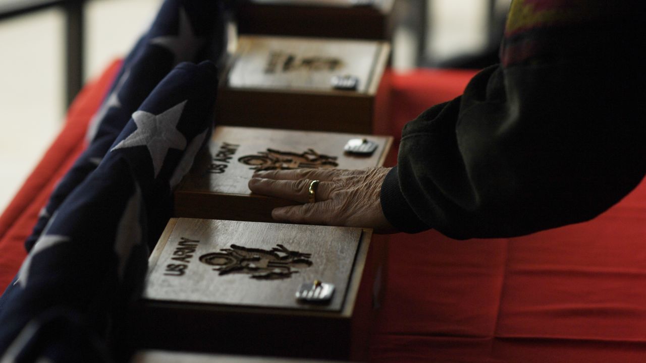 A man touches urns during a final interment ceremony in Denver on Friday, March 24. The unclaimed remains of 22 US veterans were honored at Fort Logan National Cemetery. The veterans served in wars such as World War II, the Korean War and the Vietnam War.