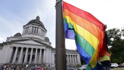 A state worker unfurls a rainbow flag in front of the Washington state Capitol to prepare it to be raised and then lowered to half-staff to mark last weekend's mass shooting at a central Florida nightclub, Wednesday, June 15, 2016, in Olympia, Wash. Gov. Jay Inslee and members from the LGBT community later raised the flag in honor of Gay Pride month, before it was lowered. A gunman wielding an assault-type rifle and a handgun opened fire inside Pulse, a crowded gay nightclub in Orlando, Florida, early Sunday, leaving at least 49 people dead in the worst mass shooting in modern U.S. history. (AP Photo/Elaine Thompson)