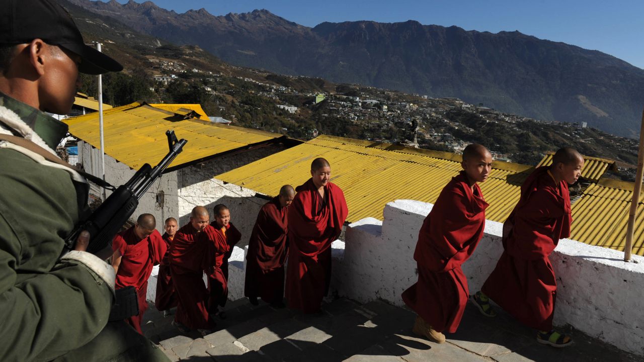 A security official, left, stands guard as monks arrive for the last visit by the Dalai Lama to Tawang Monastery in Arunachal Pradesh in November 2009.   