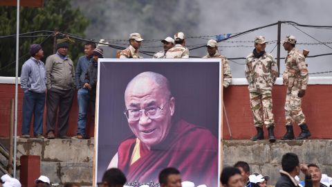 Indian security personnel stand with a poster of the Dalai Lama as he delivers religious teachings at the Buddha Stadium in Bomdila in India's northeastern state of Arunachal Pradesh state on April 5, 2017.