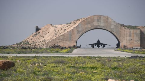 A plane is visible under an arch at the Shayrat airfield.