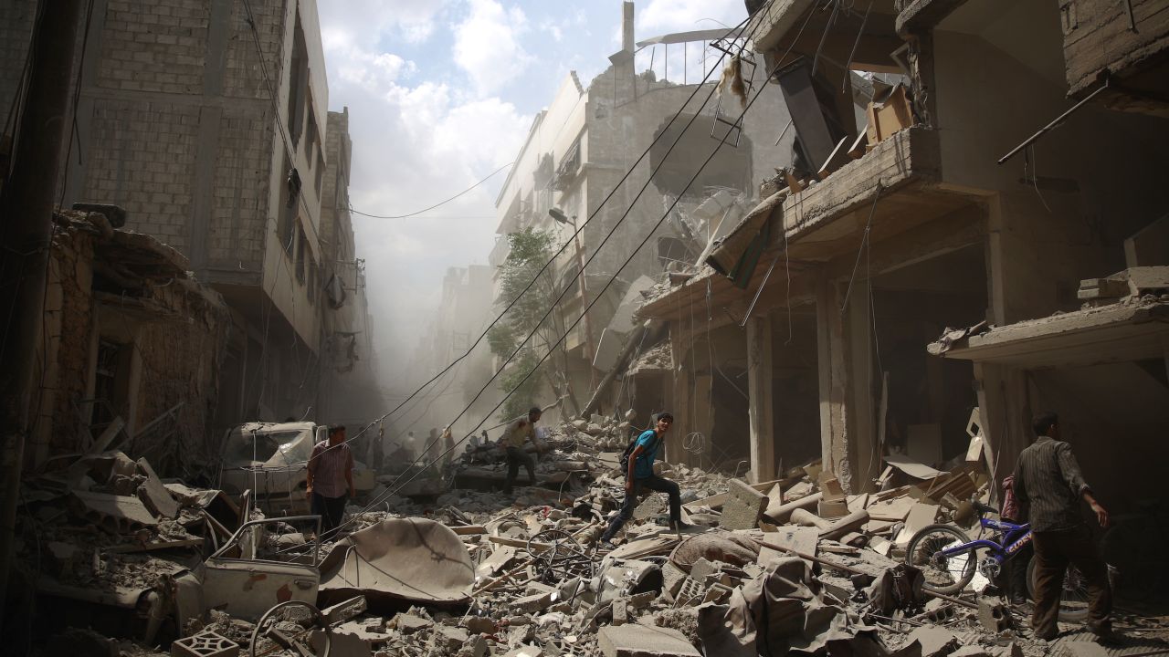 Syrians walk amid the rubble of destroyed buildings following reported air strikes by regime forces in the rebel-held area of Douma, east of the capital Damascus, on August 30, 2015. More than 240,000 people have been killed since Syria's conflict began in March 2011, and half of the country's population has been displaced by the war. AFP PHOTO / ABD DOUMANY / AFP / ABD DOUMANY (Photo credit should read ABD DOUMANY/AFP/Getty Images)