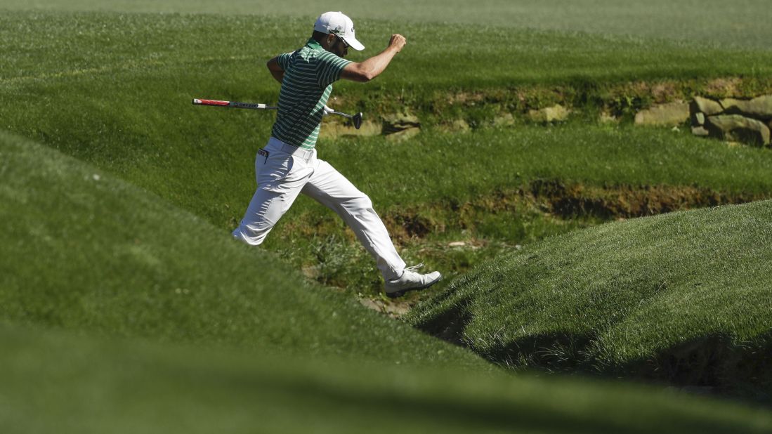 Adam Hadwin jumps across Rae's Creek while playing the 13th hole.