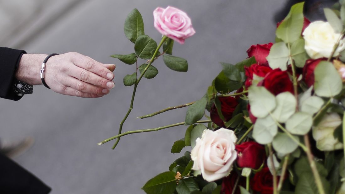 A woman tosses a flower onto the memorial in central Stockholm.