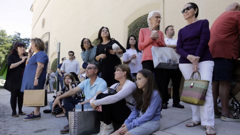 People sit outside the Shops at Merrick Park mall in Coral Gables after a shooting Saturday. 