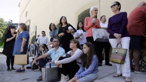 People sit outside the Shops at Merrick Park mall in Coral Gables after a shooting Saturday.