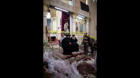 Priests sit next to security personnel investigating the scene of the bombing.