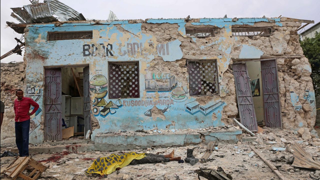 The body of a bombing victim lies in front of a building that was damaged in the attack. 