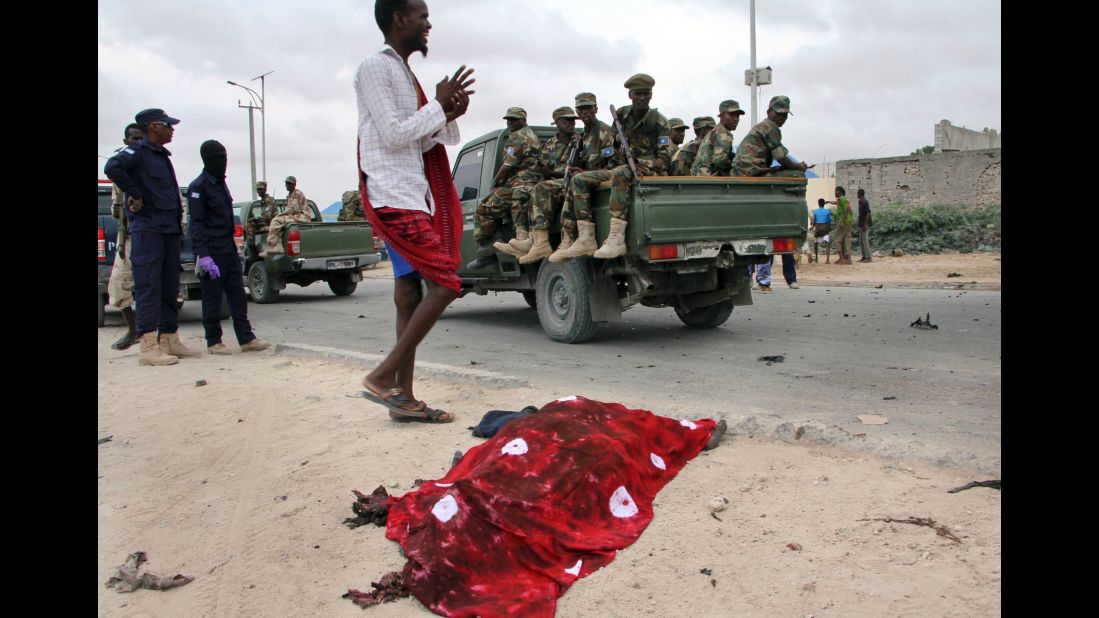 Soldiers in a truck pass by the covered body of a bomb attack victim.