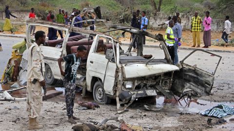 A Somali soldier stands by the wreckage of a minibus that was destroyed by the car bomb.