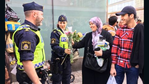 A woman in an Islamic headscarf hands flowers to police at a vigil Sunday after the Stockholm truck attack.