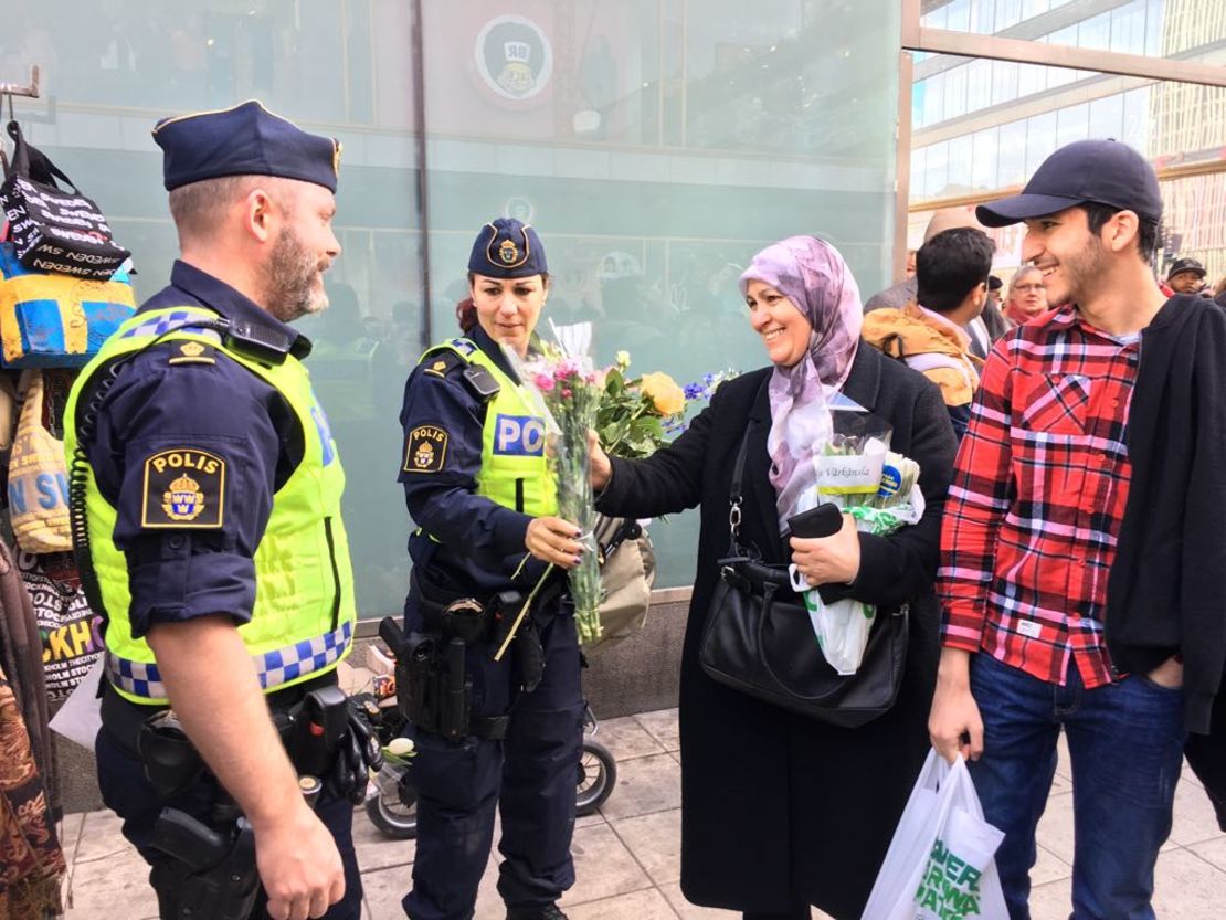 A woman in an Islamic headscarf hands flowers to police at a vigil Sunday after the Stockholm truck attack.