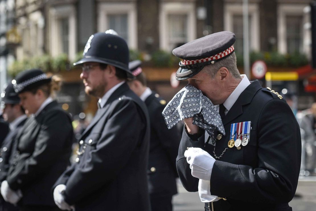 A policeman reacts during a broadcast of Palmer's funeral service from Southwark Cathedral.