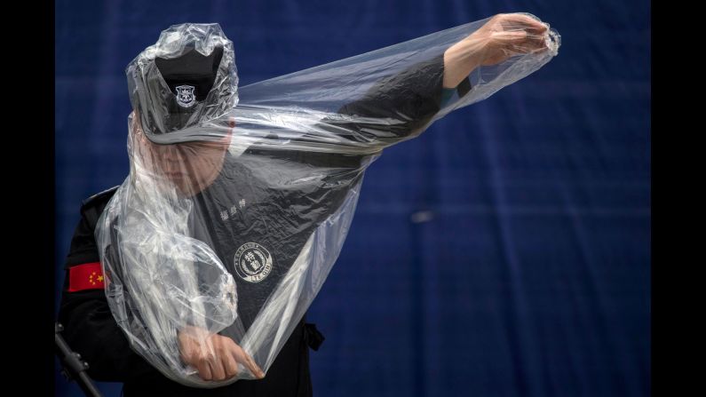 A security officer puts on a rain poncho Thursday, April 6, as he works at the site of the Formula One race in Shanghai, China.