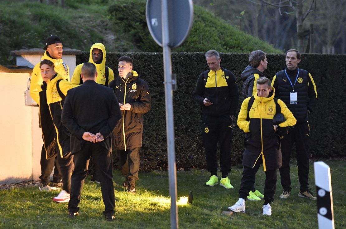 Head coach Thomas Tuchel, right, and players of Borussia Dortmund stand outside their team bus after it was damaged in an explosion.