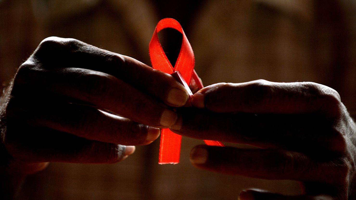 An HIV-positive person prepares red ribbons for World AIDS Day in Bangalore, India