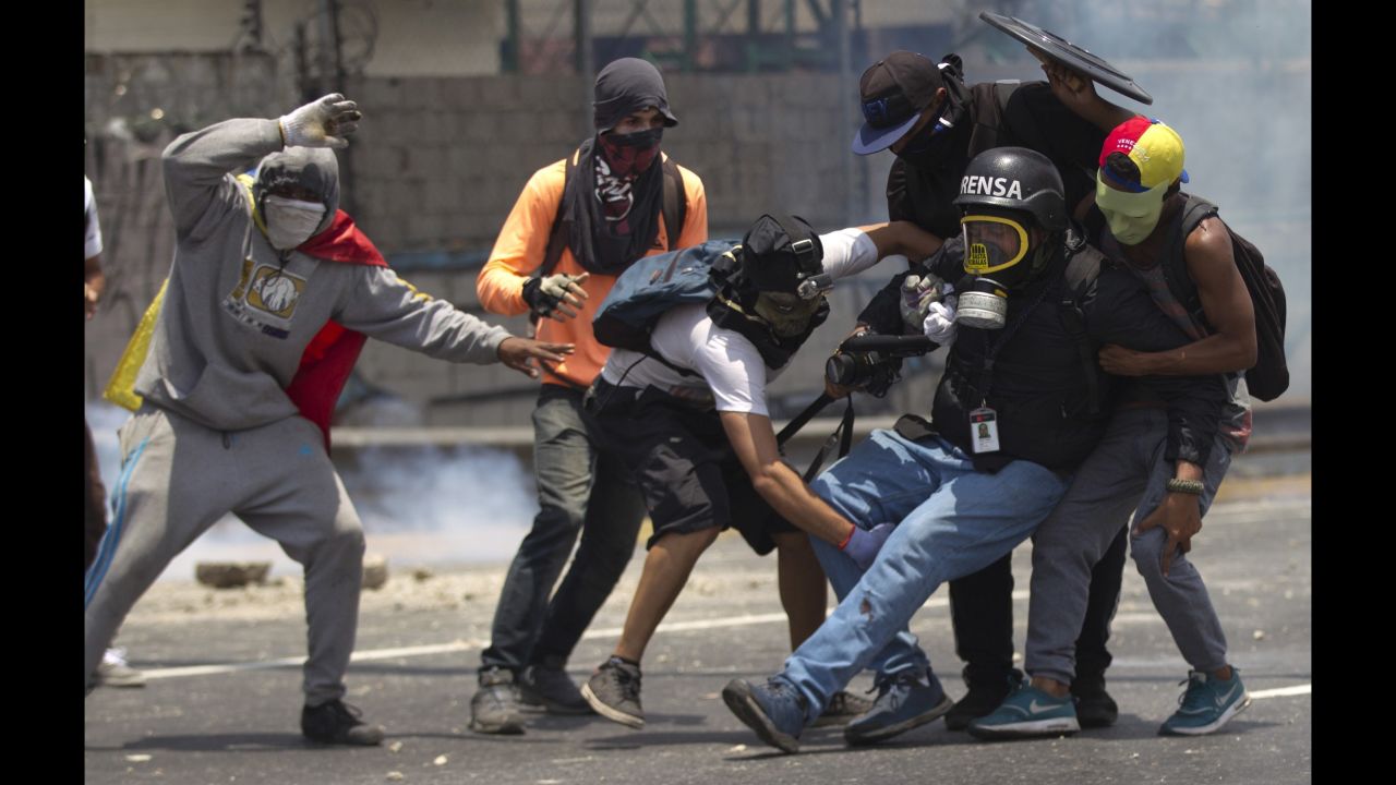 Demonstrators help a journalist whose leg was injured while covering clashes in Caracas on April 10.