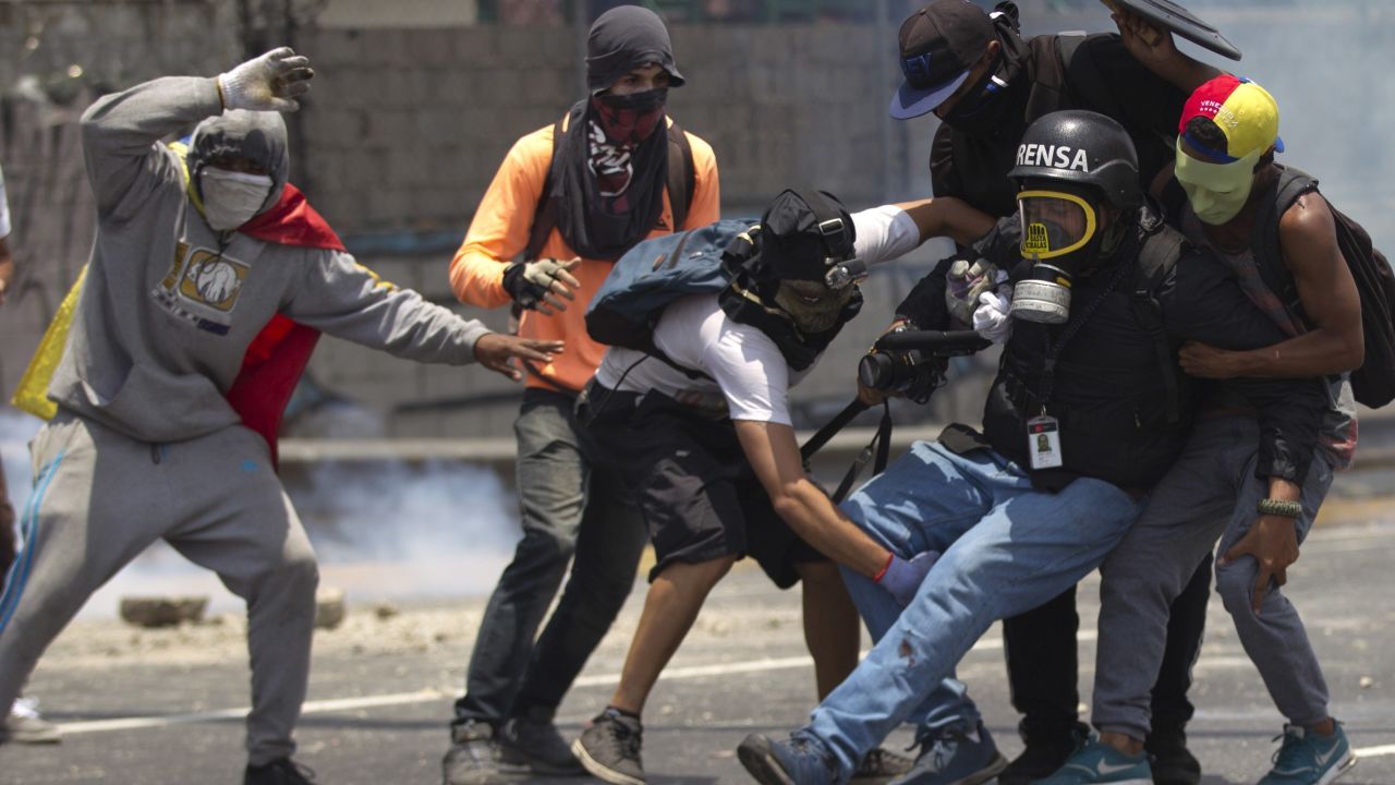 Demonstrators help a journalist who was injured in a leg while covering clashes between demonstrators and the  Bolivarian National Guard during a protest in Caracas, Venezuela, Monday, April 10, 2017. Opponents of President Nicolas Maduro protested on the streets of the capital as part of an ongoing protest movement that shows little sign of losing steam. 
