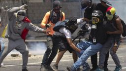 Demonstrators help a journalist who was injured in a leg while covering clashes between demonstrators and the  Bolivarian National Guard during a protest in Caracas, Venezuela, Monday, April 10, 2017. Opponents of President Nicolas Maduro protested on the streets of the capital as part of an ongoing protest movement that shows little sign of losing steam.