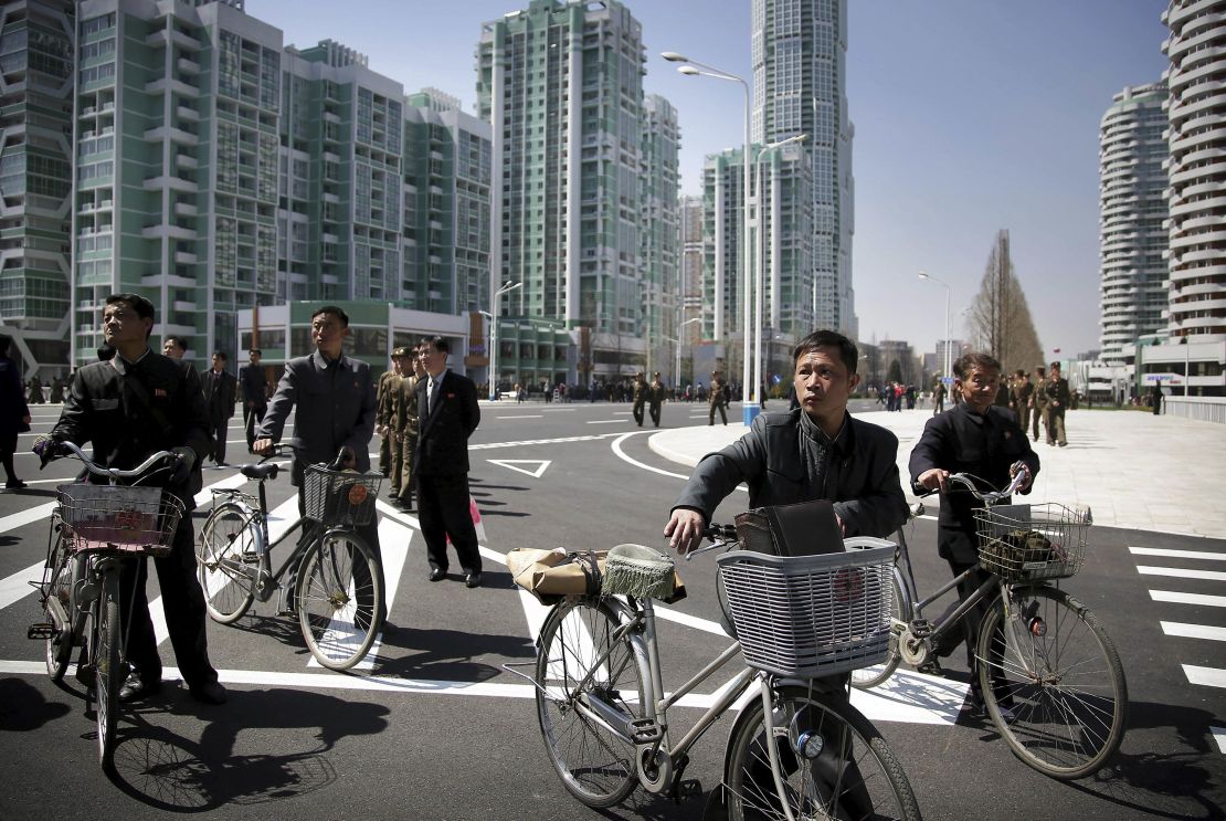 Men wheel their bicycles through the Ryomyong Street complex.