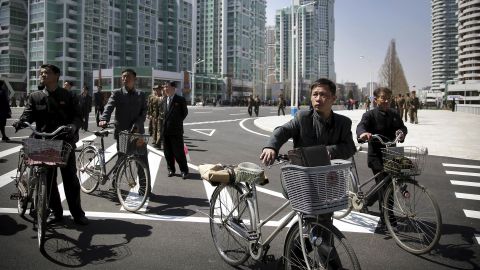 Men wheel their bicycles through the Ryomyong Street complex.