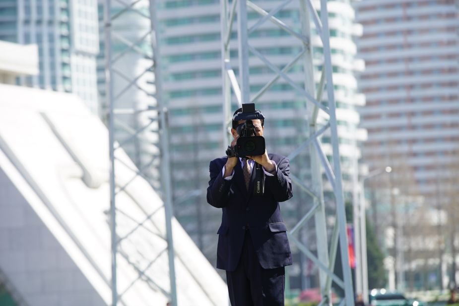 Foreign journalists are filmed by North Korean media during the Ryomyong Street event.