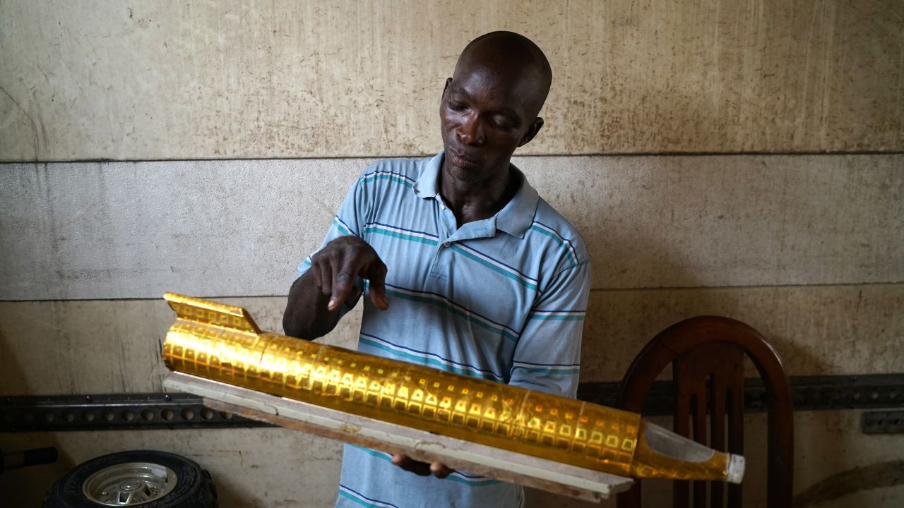 Kehinde inside his workshop explaining the principles of his jetcar with this model.