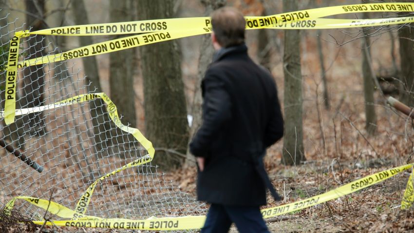 A man walks past police tape near a crime scene in Central Islip, N.Y., Thursday, April 13, 2017. Police say the bodies of four apparent homicide victims have been found in a Long Island park. The victims were found in a wooded area near a recreation center in Central Islip. (AP Photo/Seth Wenig)