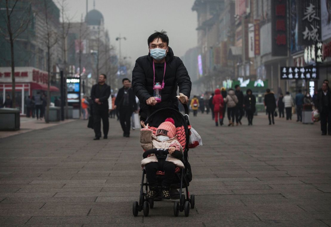  A Chinese man and his child wear masks to protest against pollution as they walk through a shopping area in heavy smog on December 8, 2015 in Beijing, China.