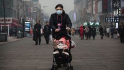 BEIJING, CHINA - DECEMBER 08:  A Chinese man and his child wear masks to protest against pollution as they walk through a shopping area in heavy smog on December 8, 2015 in Beijing, China. The Beijing government issued a "red alert" for the first time since new standards were introduced earlier this year as the city and many parts of northern China were shrouded in heavy pollution. Levels of PM 2.5, considered the most hazardous, crossed 400 units in Beijing, lower than last week, but still nearly 20 times the acceptable standard set by the World Health Organization. The governments of more than 190 countries are meeting in Paris to set targets on reducing carbon emissions in an attempt to forge a new global agreement on climate change. (Photo by Kevin Frayer/Getty Images)
