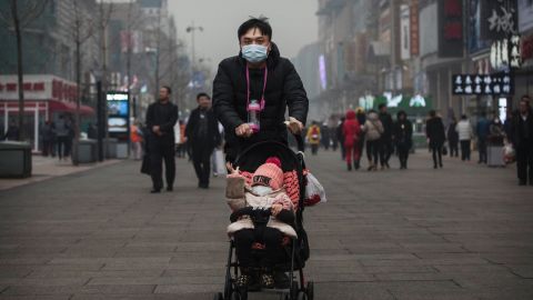  A Chinese man and his child wear masks to protest against pollution as they walk through a shopping area in heavy smog on December 8, 2015 in Beijing, China.