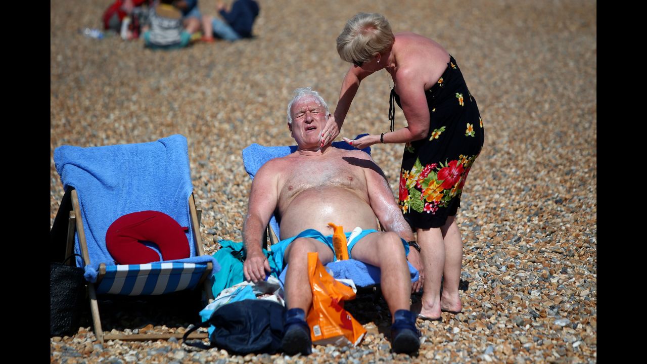 A woman rubs sunscreen on a man as they relax on a beach in Brighton, England, on Sunday, April 9.