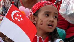 A girl holding the Singapore flag sings along during an event to celebrate Singapore's 44th National Day on August 9, 2009. In his National Day message Singapore Prime Minister Lee Hsien Loong indicated that Singapore's economic contraction in the first half of the year was not as bad as feared and that the country is now in a stronger position than at the start of the year. AFP PHOTO (Photo credit should read AFP/AFP/Getty Images)