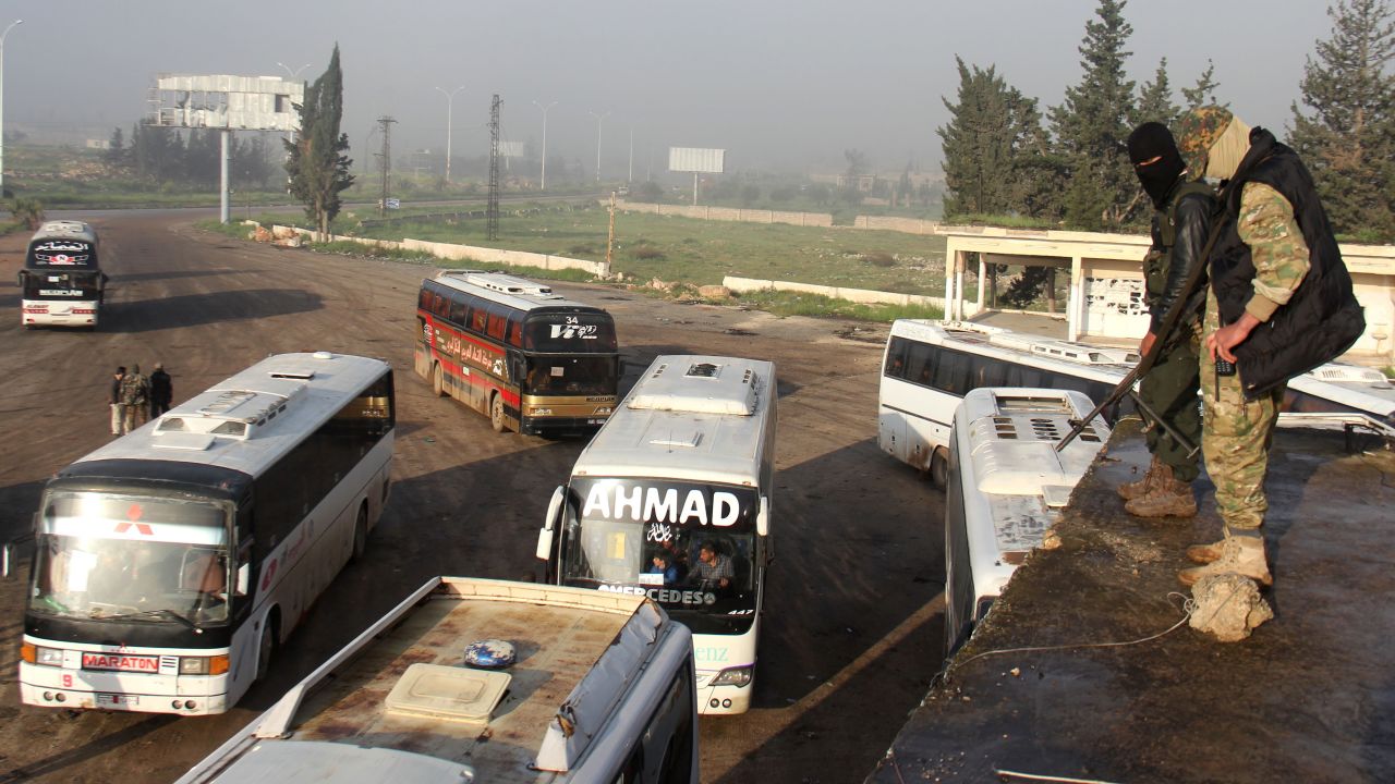 Opposition fighters monitor a bus convoy in rebel-held Rashidin, west of Aleppo, on Friday. 