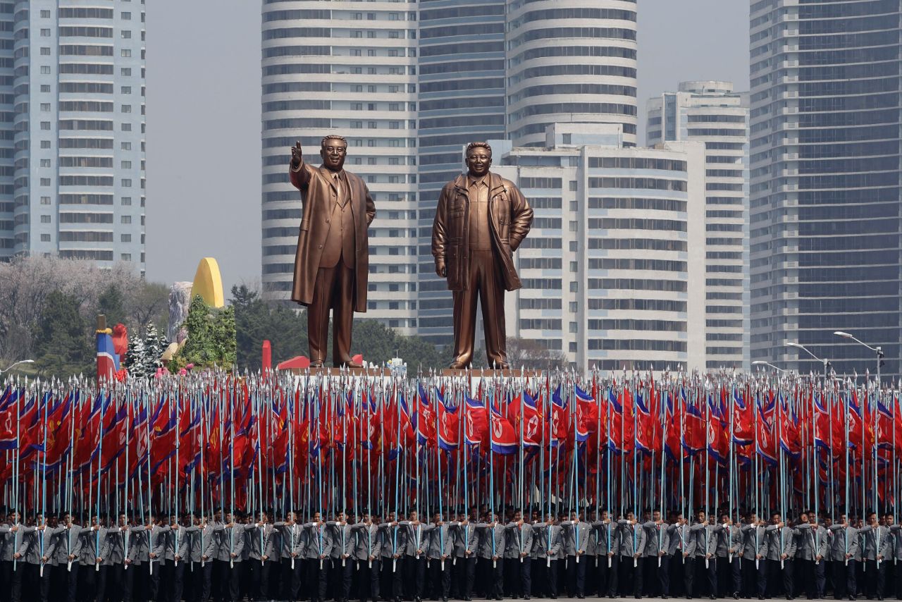 University students carry the national flag and two bronze statues of the late leaders Kim Il Sung and Kim Jong Il.