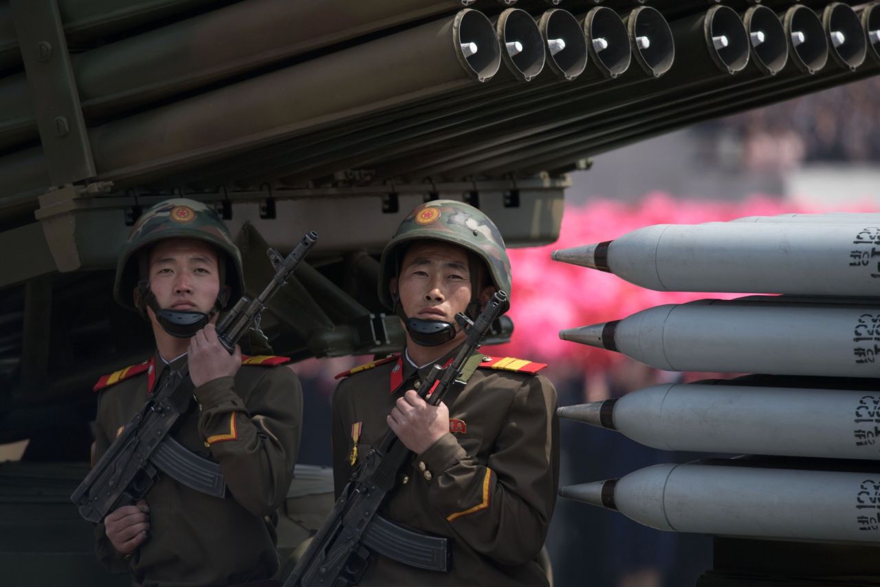 Members of the Korean People's Army ride on mobile missile launchers.