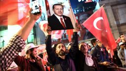 A supporter of the "yes" brandishes a picture of Turkish president Recep Tayyip Erdogan among other supporters waving Turkish national flags during a rally near the headquarters of the conservative Justice and Development Party on April 16, 2017 in Istanbul after the initial results of a nationwide referendum that will determine Turkey's future destiny.
