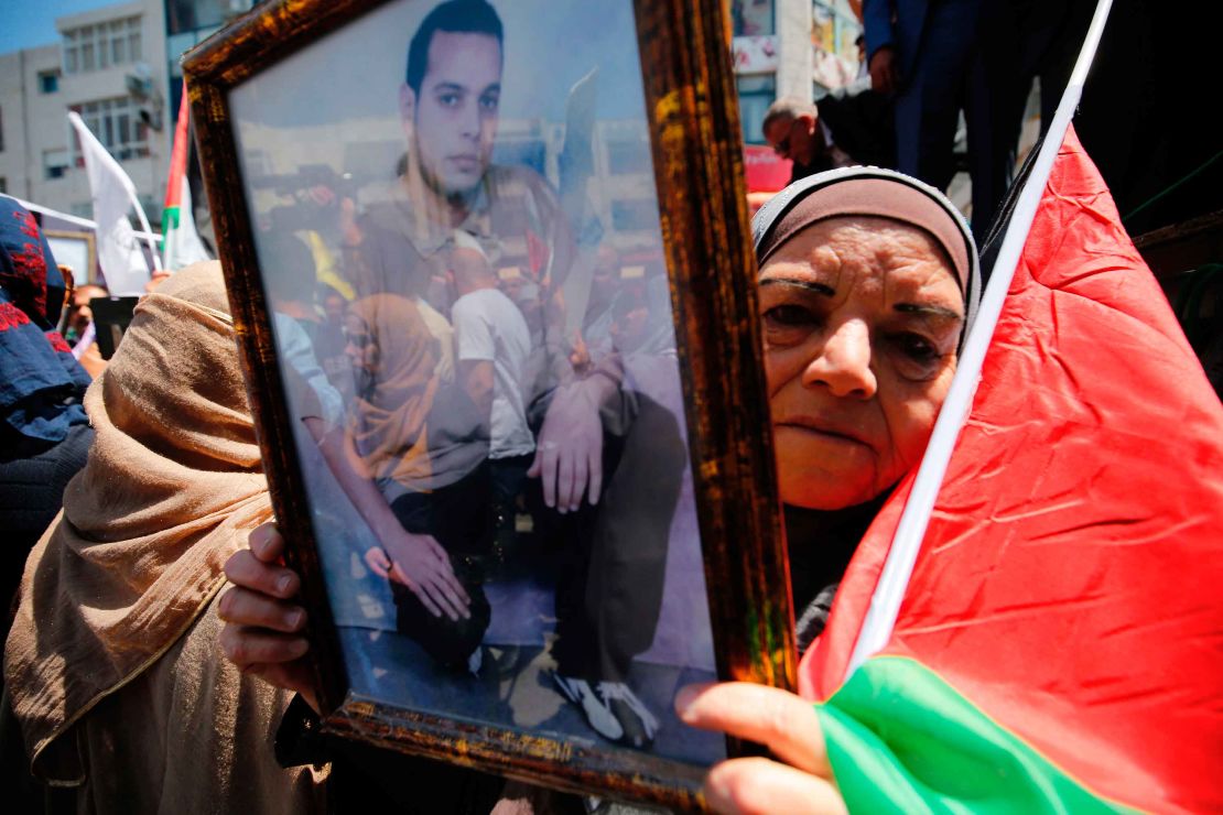 A woman holds the portrait of a Palestinian prisoner during a rally in Ramallah Monday.