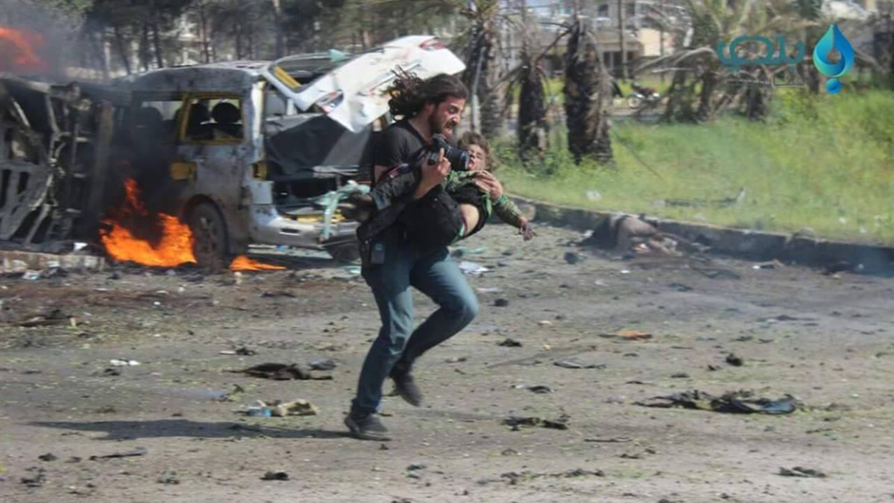 After a bombing in Syria, photographer Abd Alkader Habak runs towards safety with a child in his arms.