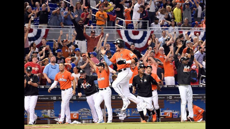 Miami shortstop Miguel Rojas leaps to home plate after pinch-hitter J.T. Riddle hit a walk-off two-run homer against New York in Miami on Sunday, April 16. It was Riddle's first major league home run, and his team won 4-2.