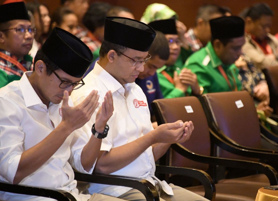 Anies Baswedan (2L) and his running mate pray during an event in Jakarta on March 4.
