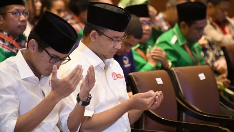 Anies Baswedan (2L) and his running mate pray during an event in Jakarta on March 4.