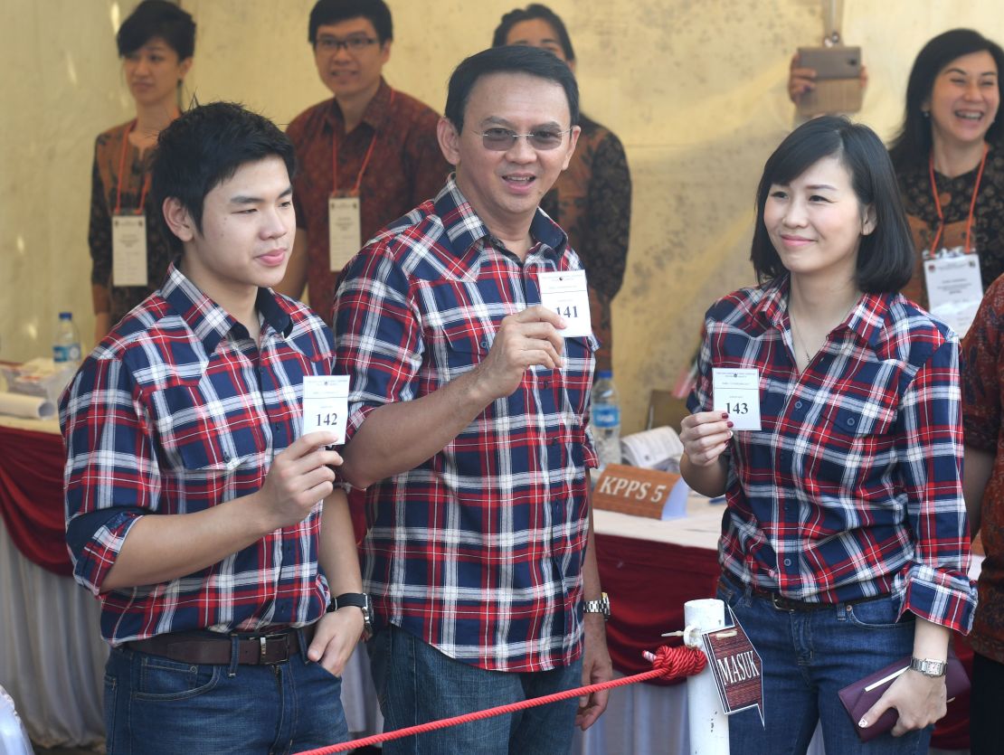 Ahok flanked by his wife Veronica (R) and son Nicholas (L) show off their first-round ballot papers in Jakarta on February 15.