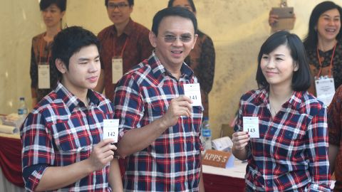 Ahok flanked by his wife Veronica (R) and son Nicholas (L) show off their first-round ballot papers  in Jakarta on February 15.