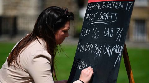 An employee from a betting company writes odds on a blackboard outside the Houses of Parliament.