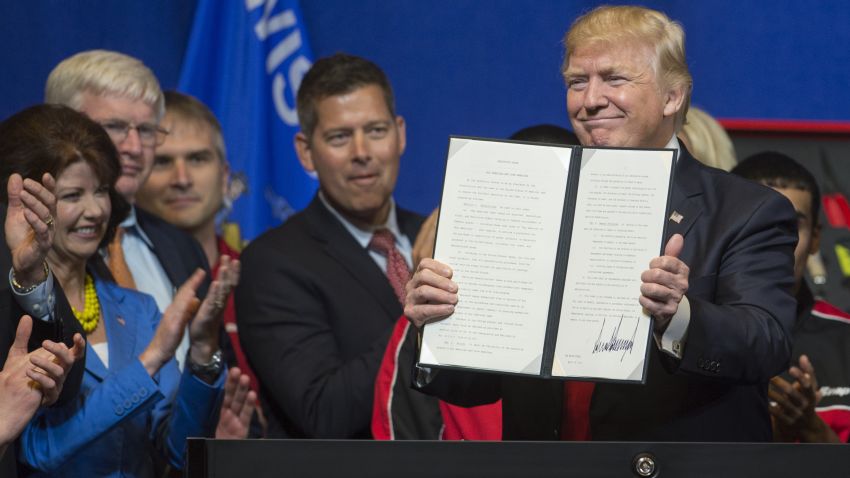 US President Donald Trump holds up a Buy American, Hire American Executive Order after signing at Snap-On Tools in Kenosha, Wisconsin, April 18, 2017. / AFP PHOTO / SAUL LOEB        (Photo credit should read SAUL LOEB/AFP/Getty Images)