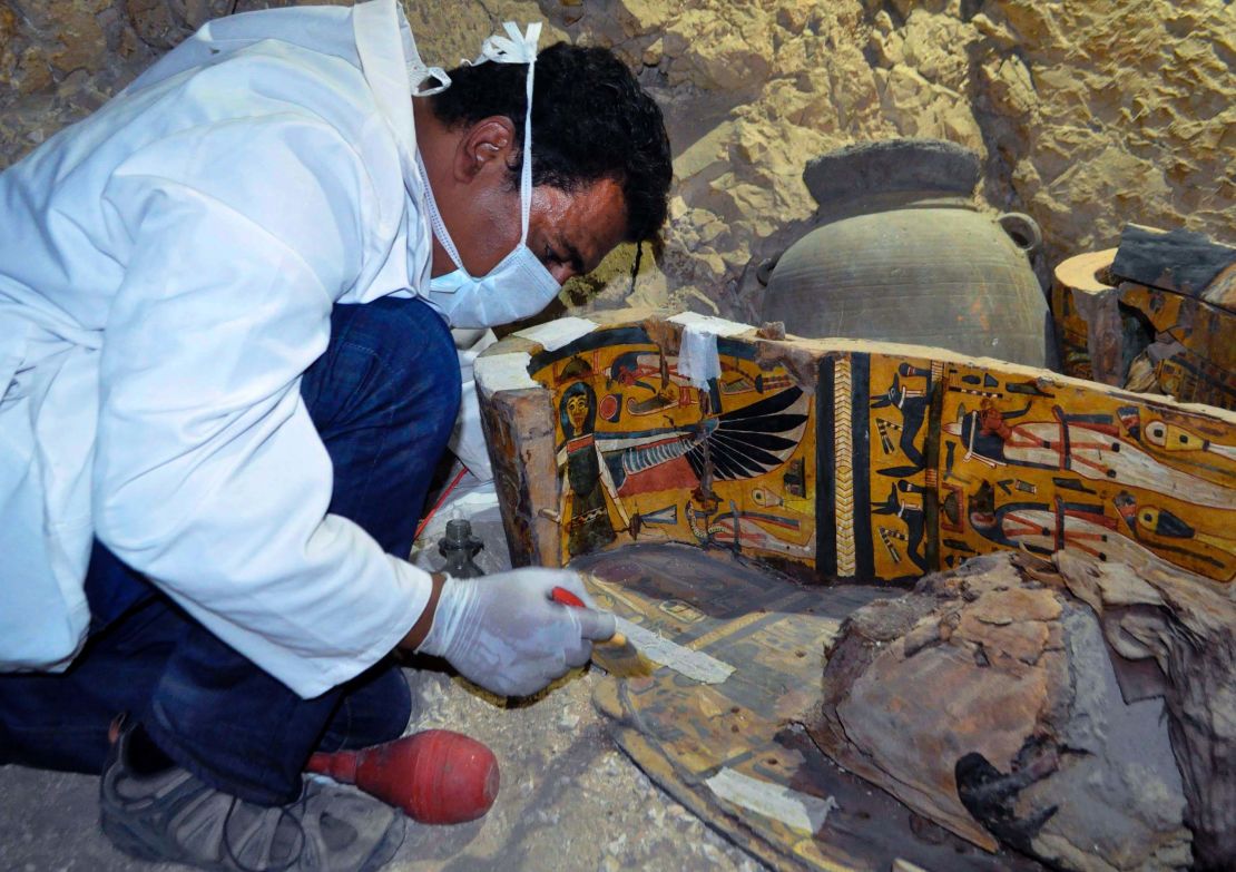 A member of the Egyptian archaeological team works on a wooden coffin Tuesday.