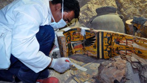 A member of the Egyptian archaeological team works on a wooden coffin Tuesday.